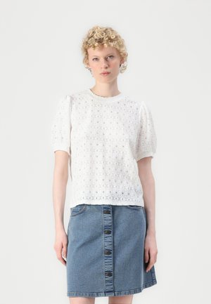 Blouse en dentelle blanche avec des manches bouffantes, encolure ronde, associée à une jupe en denim avec une fermeture à boutons à l'avant et deux poches.