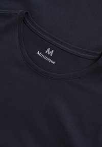 Tamsiai mėlynas marškinėliai su apvalia kaklo išpjova, pagaminti iš minkštos medvilnės, su "Matinique" logotipu ir dryžuotu "M" akcentu ant apykaklės.