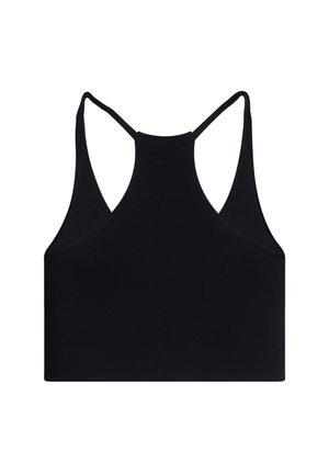 Kvinde med langt brunt hår i hestehale iført sort racerback sports-bh og sorte leggings med høj talje, vendt væk mod en ensartet baggrund.