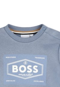 T-shirt in cotone azzurro con maniche corte e collo a coste. Presenta un logo e grafiche bianche stampate sul davanti.