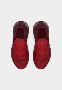 Ζευγάρι κόκκινα αθλητικά παπούτσια Reebok με κορδόνια, επάνω μέρος από δίχτυ και λογότυπο στη γλώσσα, φωτογραφημένα από ψηλά σε λευκό φόντο.