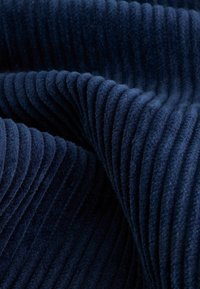 Tissu bleu marine profond avec des côtes verticales proéminentes et moelleuses, créant une apparence douce et texturée. Convient pour l'ameublement ou la mode.