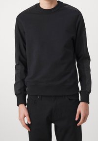 Svart sweatshirt med rund halsringning, med långa ärmar som har kontrasterande materialpaneler samt ribbade muddars och nederkant. Slät textur.