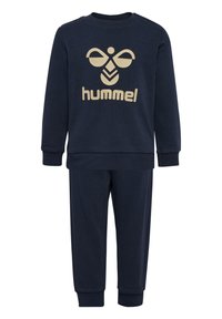 Ensemble de survêtement en coton bleu marine avec manches longues et pantalon. Présente un design de logo beige à l'avant. Les poignets et la taille sont côtelés.