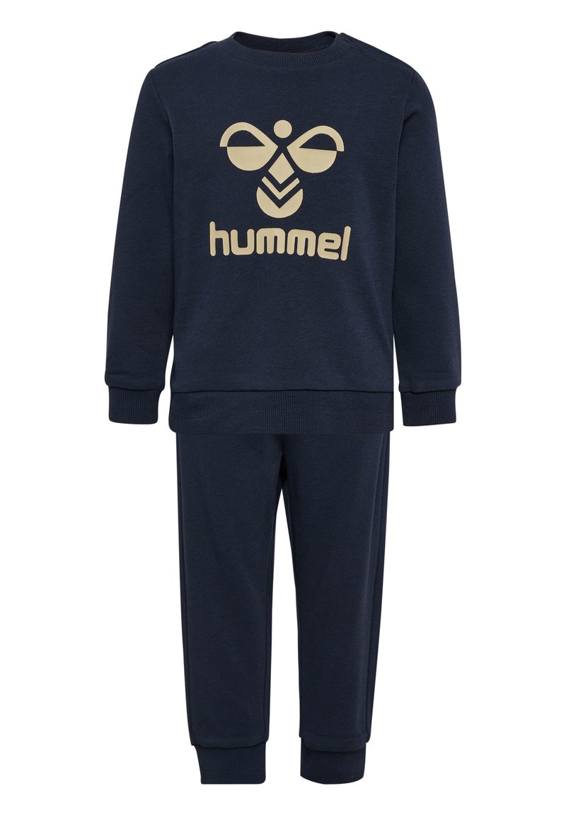 Ensemble de survêtement en coton bleu marine avec manches longues et pantalon. Présente un design de logo beige à l'avant. Les poignets et la taille sont côtelés.