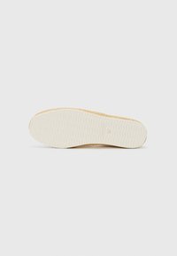 Sole of a shoe featuring a textured white surface with subtle wavy patterns, bordered by a beige, natural material.