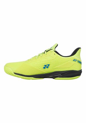 Scarpa da ginnastica di un giallo brillante con suola e interno neri, loghi blu Yonex sul lato e sul tallone, progettata per prestazioni sportive.