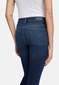 Dunkelblaue Denim-Jeans mit hoher Taille, geradem Schnitt, zwei Gesäßtaschen und subtilen Steppnähten.