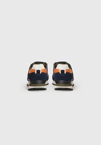 Sneaker mit einem marineblauen Textil-Obermaterial, orangefarbenen und weißen Akzenten, gepolstertem Kragen und schwarzer Gummisohle. Die Rückansicht zeigt kontrastierende Texturen.