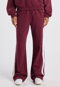 Burgundiväriga sweatpants med en avslappnad passform, med vita sidostr�äck, elastisk midja och mjukt, texturerat tyg.
