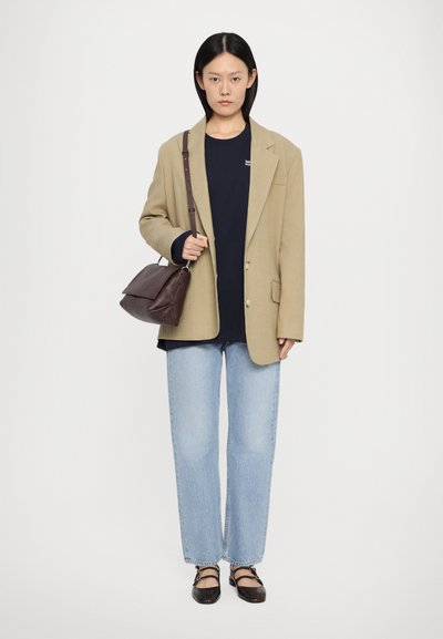 Beige blazer, sötétkék póló, világoskék farmere és barna kézitáska. Fonott textúrájú lapos cipők. Minimalista dizájn, laza fit.