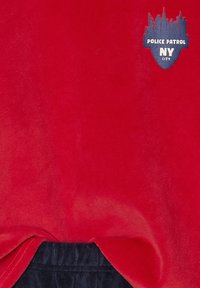 Rotes Baumwollhemd mit einem navyblauen unteren Saum, versehen mit einem blauen und weißen "POLICE PATROL NY CITY" Logo und einer Skyline-Grafik.