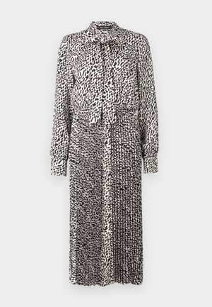 Black and white patterned dress with a collar, long sleeves, tie detail at neck, and pleated skirt, made from lightweight fabric.