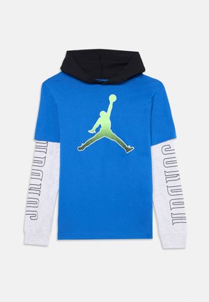 Blå og sort hættetrøje med hvide ærmer med teksten "JORDAN" og en grøn silhuet af en basketballspiller på brystet.