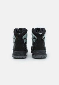 Bocanci de exterior cu gamba înaltă, cu un design negru și teal, plasă texturată, vârf întărit și o talpă robustă din cauciuc negru pentru aderență.