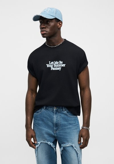 Čierne oversize tričko s bielym textom, kombinované so svetlomodrými roztrhanými džínsami a svetlomodrou šiltovkou. Doplnky zahŕňajú strieborný retiazkový náhrdelník.