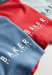 Dušo medvilnės marškiniai, vienas raudonas ir vienas mėlynas, su ryškiai baltais „BAKER by Ted Baker“ logotipais. Lygus paviršius ir laisvas kirpimas.