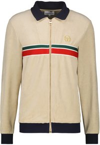 Beige Jacke mit Reißverschluss und blauer Kragen, mit horizontalen roten und grünen Streifen. Weiches Veloursmaterial mit einem goldenen Logodetail.