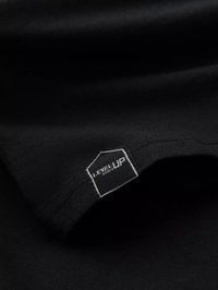 Schwarzes Baumwoll-T-Shirt mit einem hexagonalen "LEVEL UP"-Label und weißen Nähten. Glatte Textur und minimalistisches Design.