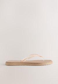 Tongs beige avec bride pailletée, semelle texturée et base en caoutchouc plate, vues de côté sur fond neutre.