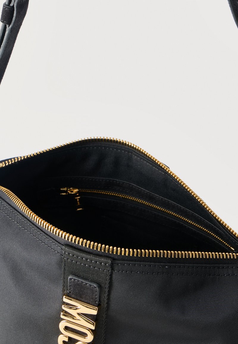 Black handbag with gold zipper partially open, showing black fabric interior and an inner zippered pocket.