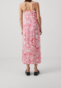 Sukienka maxi na cienkich ramiączkach, z różowo-białym kwiatowym wzorem na lekkim materiale. Posiada elastyczną talię dla dopasowania.
