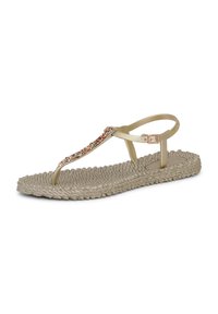 Sandalia plana beige con suela texturizada tejida, tira en T adornada con gemas multicolores y correa ajustable con hebilla en el tobillo.