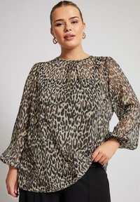 Blusa trasparente a maniche lunghe con stampa leopardata, dotata di scollo rotondo, dettagli arricciati e un orlo leggermente curvo.
