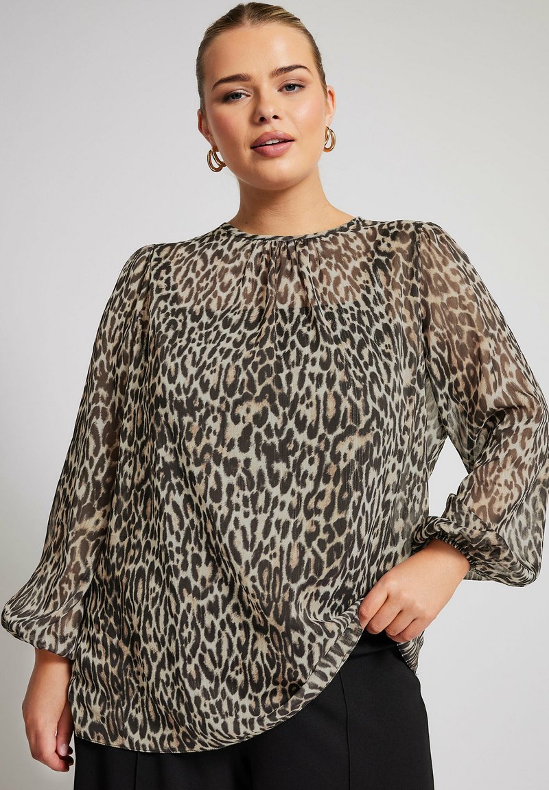 Blusa trasparente a maniche lunghe con stampa leopardata, dotata di scollo rotondo, dettagli arricciati e un orlo leggermente curvo.