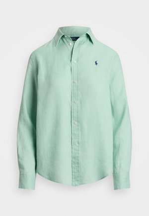 Világoszöld vászon ing hosszú ujjal, gombos gallérral és egy kis sötétkék logóval a bal mellen. Puha textúra, kényelmes szabás.