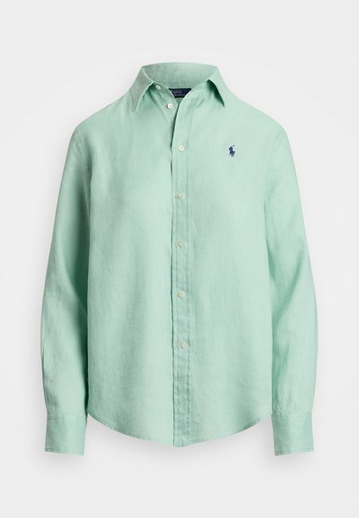 Šviesiai žalia lininė marška su ilgomis rankovėmis, mygtukų apačioje ir mažu tamsiai mėlynu logotipu kairėje krūtinės pusėje. Minkšta tekstūra, laisvas kirpimas.