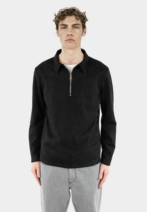Svart långärmad tröja med zipkrage, gjord av mjukt, glansigt tyg, med en minimalistisk design och en avslappnad passform.