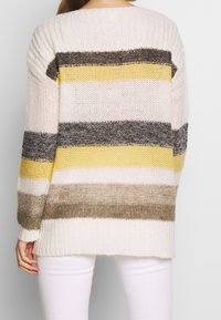 Maglione a maglia color crema con righe orizzontali in diverse tonalità di giallo, beige, grigio e marrone. Vestibilità ampia con dettagli a costine ai polsini.
