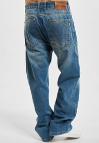 Blå denimjeans med en avslappet passform, med et lærbelte-merke, broderte baklommer og en falmet vasketekstur.