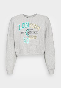 Ljusgrå kortärmad sweatshirt med turkosa och guldiga grafik som visar texten "LON SO YORK KLYN", med ribbade ärm- och midjeresår.