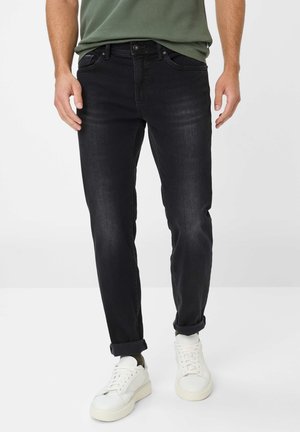 Zwarte denim jeans met een slim fit, voorzien van standaard zakken, een knoopsluiting en omgeslagen boorden, gecombineerd met witte sneakers.
