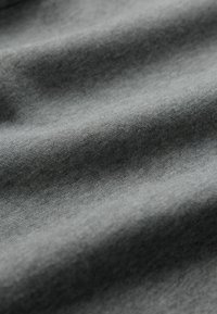 Ciemnoszara tkanina o miękkiej, lekko teksturowanej powierzchni, pokazująca delikatne fałdy i zagniecenia, wskazujące na luźno tkane splot.