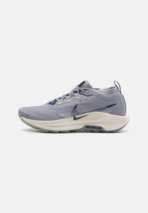Chaussure de trail Nike violet clair avec tissu Gore-Tex, semelle intermédiaire blanche, logo swoosh foncé et semelle extérieure verte, vue du côté extérieur.