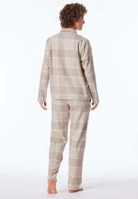 Beige rutiga pyjamasar gjorda av mjukt tyg, med en knapp-up skjorta och byxor med elastisk midja och avslappnad passform.