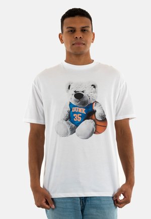 Camiseta blanca con un gráfico de un oso de peluche gris en una camiseta azul con la palabra "DUNK" y el número "35", sosteniendo un balón de baloncesto.