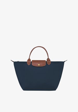 Marineblaue Tragetasche mit braunen Ledergriffen und Klappe, ausgestattet mit einem Reißverschluss und einer Vordertasche. Hergestellt aus strapazierfähigem, wasserabweisendem Material.
