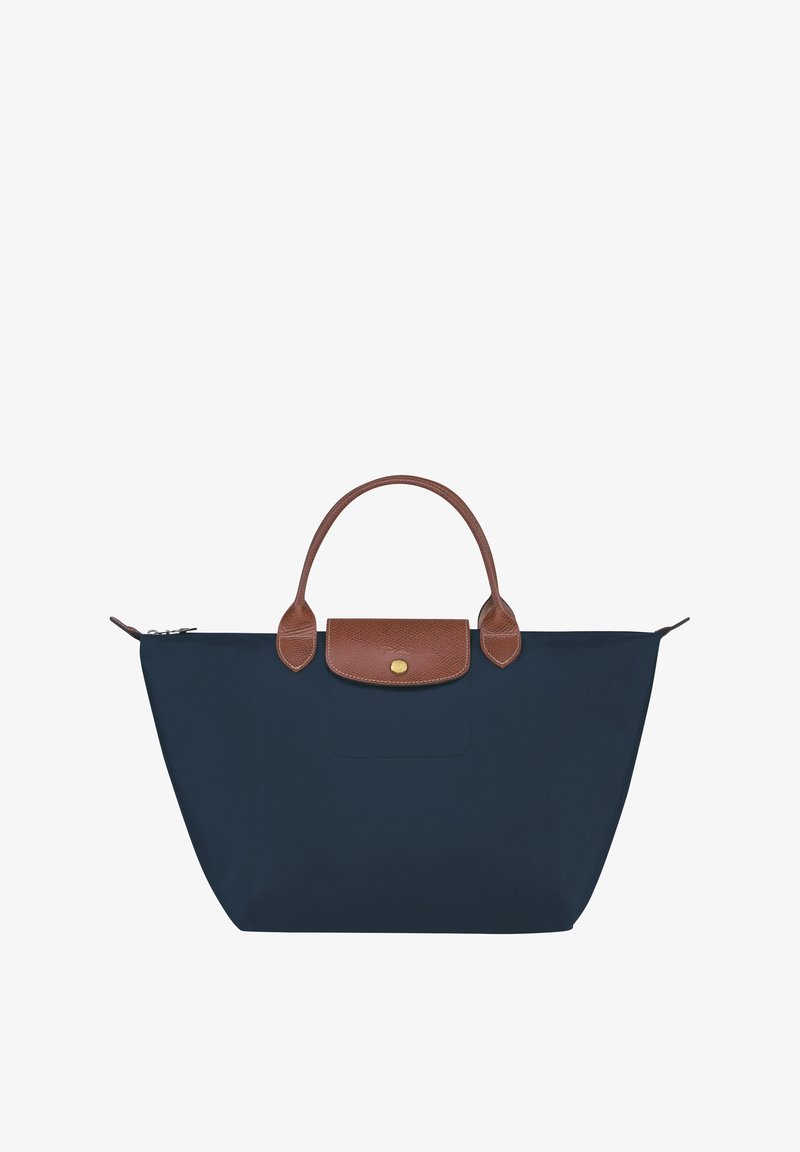 Navy blue tote bag with brown leather handles and flap, features a zippered closure and a front pocket. Made from durable, water-resistant material.