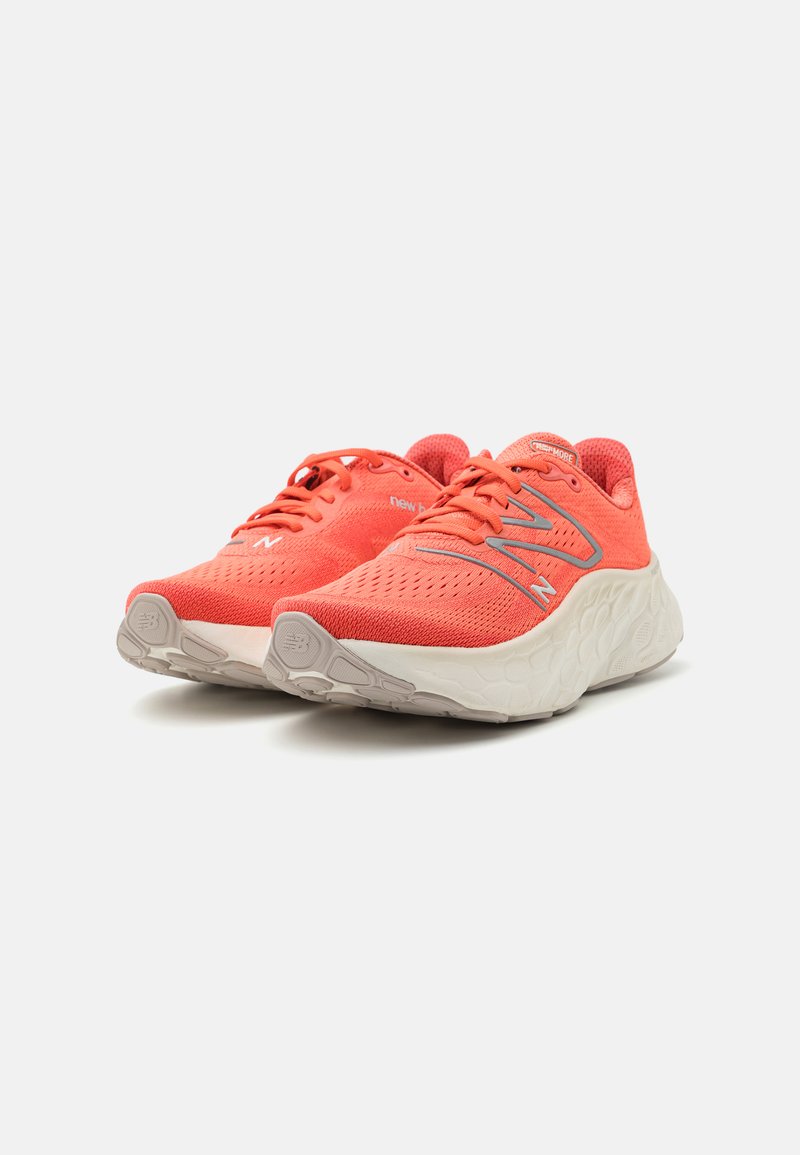 Helle Korallen-Laufschuhe mit atmungsaktiven Mesh-Obermaterial, kontrastierenden silbernen Akzenten und gepolsterten weißen Sohlen mit strukturierten Mustern.