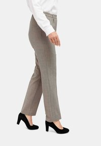 Grau karierte Hose mit schmalem Schnitt, elastischem Bund und Fronttaschen, kombiniert mit schwarzen Wildleder-High Heels.