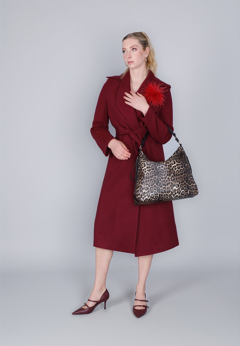 Bordeauxfärgad omslagsoverall med knytmidja, i kombination med en väska med leopardmönster och bordeauxfärgade högklackade skor. Röd fjädraccent på kappan.