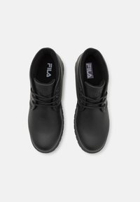 Botas de tobillo de cuero negro con puntera redonda, cierre de cordones, cuello acolchado y suela de goma texturizada. Logo de Fila en la lengüeta.