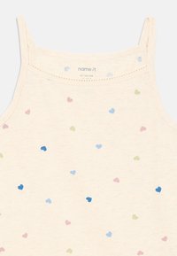 Light cream tank top with thin straps, featuring a scattered pattern of small colored hearts in blue, pink, and green. Cotton material.