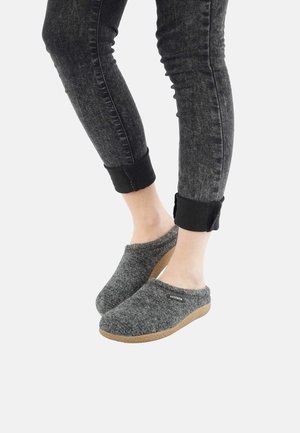 Gray felt slippers with a low profile, cork sole, and subtle branding detail. Paired with dark, rolled-cuff jeans. Soft texture.