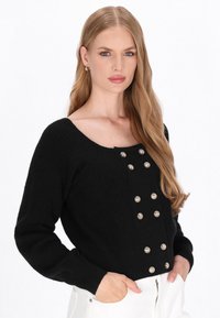 Czarny sweter ze ribbowanego dzianiny z kwadratowym dekoltem, z ozdobami z srebrnych guzików na przodzie i długimi rękawami. Prosty i fakturowany design.
