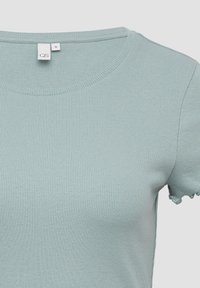 Hellblaue gerippte Strick-Bluse mit kurzen Ärmeln und rundem Ausschnitt sowie einem kleinen Größenetikett mit der Bezeichnung "S" am Kragen.